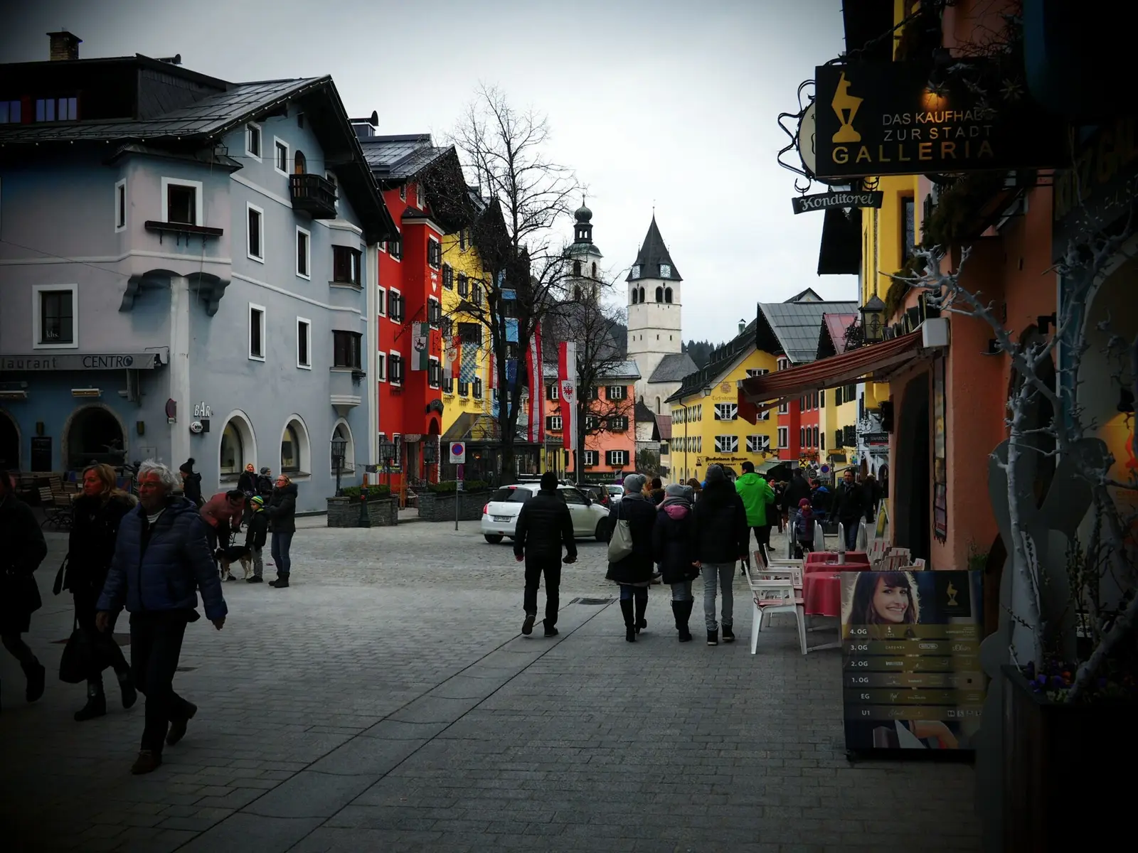Colourful old town street in Kitzbuehel with church tower behind
